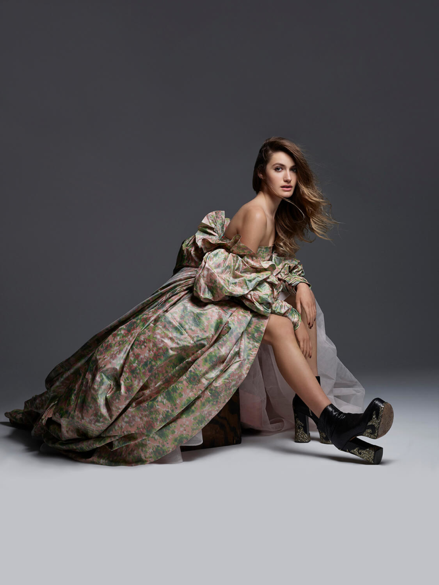 Actress and Singer Nicole Berger, in green and pink puffy gown with puff sleeves, profile view, showing leg and her black platform boots. Shot by Mark Seliger